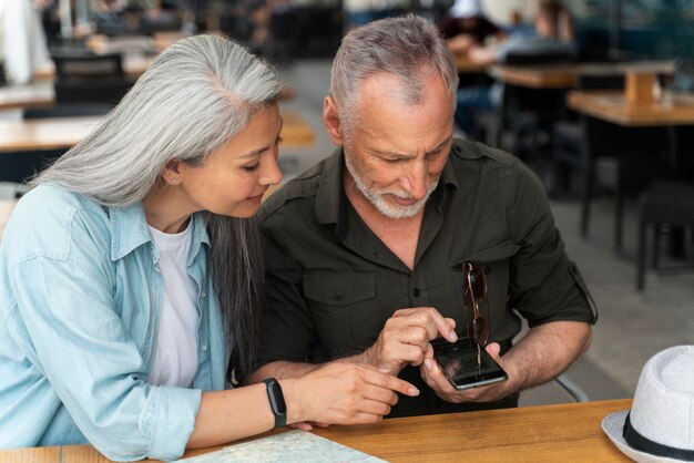 Couple de personnes âgées à plan moyen avec smartphone