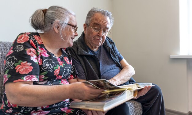 Un couple de personnes âgées regarde des photographies dans un album de photos de famille.