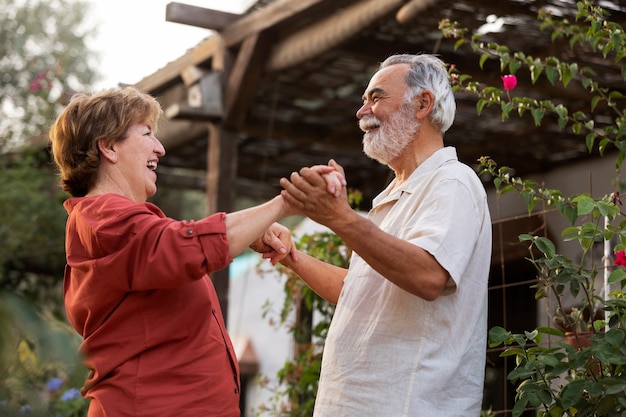 Couple de personnes âgées se tenant romantiquement dans leur jardin de campagne