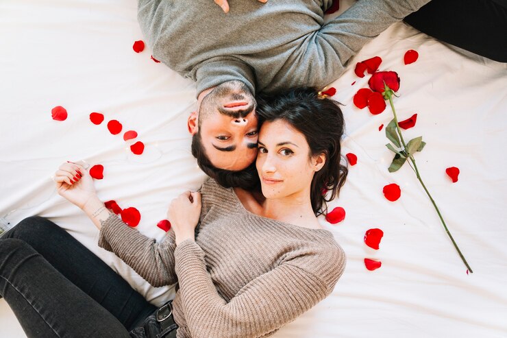Photo gratuit couple sur les pétales de rose en regardant la caméra