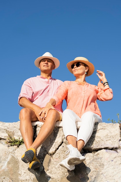 Photo gratuite couple plein coup assis sur la falaise