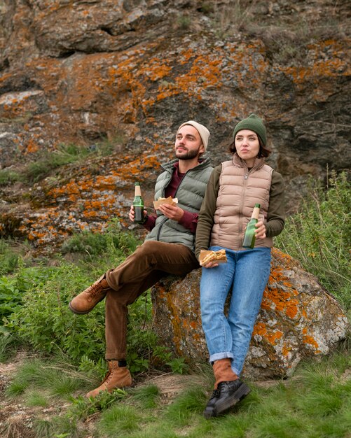 Couple plein coup assis sur un rocher et prendre un verre