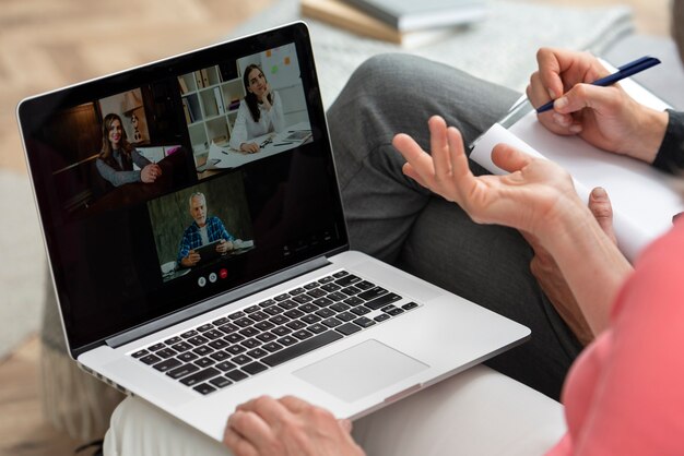 Couple plus âgé à la maison sur le canapé ayant un appel vidéo sur un ordinateur portable