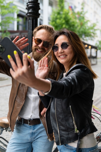 Couple portant des vestes en cuir synthétique prenant selfie ensemble à l'extérieur