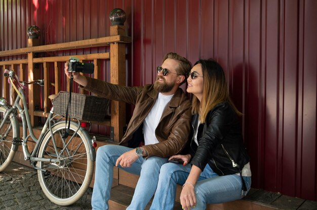 Couple portant des vestes en cuir synthétique prenant selfie ensemble à l'extérieur