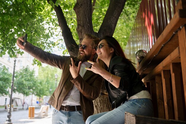 Couple portant des vestes en cuir synthétique prenant selfie ensemble à l'extérieur