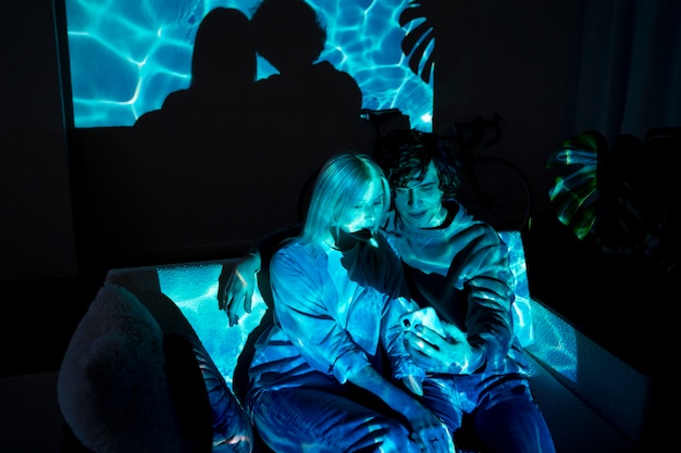 Couple prenant des photos à la lumière d'un projecteur de cinéma