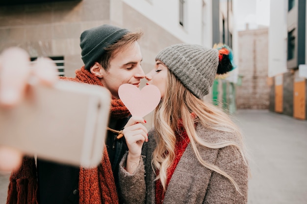 Couple prenant selfie avec coeur de papier