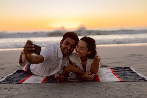 Couple prenant selfie avec téléphone portable sur la plage