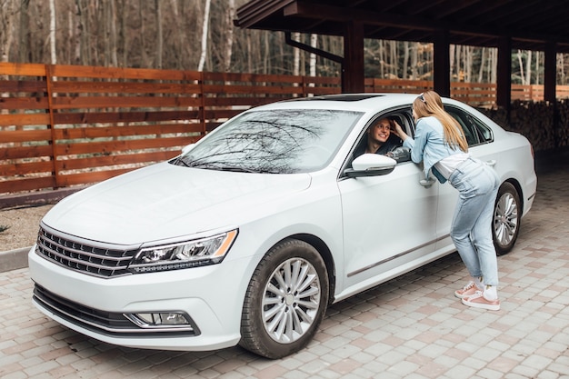 Couple près de la nouvelle voiture blanche. Un homme se rend au travail et sa femme l'attend.