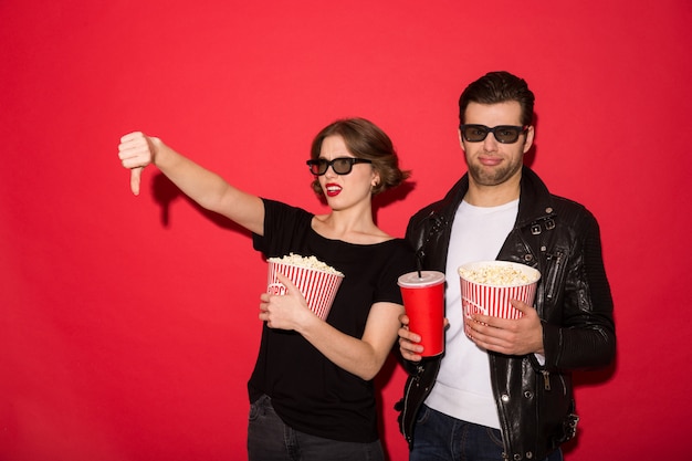 Couple punk mécontent à lunettes avec pop-corn et soda