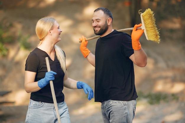 Photo gratuite couple ramasse des feuilles et nettoie le parc