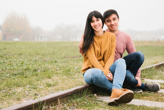 Couple ravi assis sur des rails et câlins