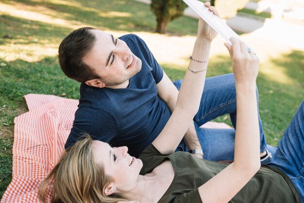 Couple regardant tablette dans le parc