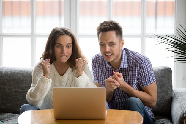 Couple, regarder, ordinateur portable, soutenir, équipe, regarder match, ligne