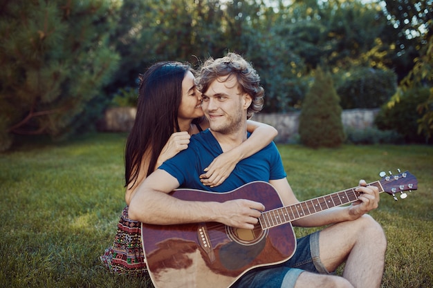 Couple romantique assis sur l'herbe dans le jardin