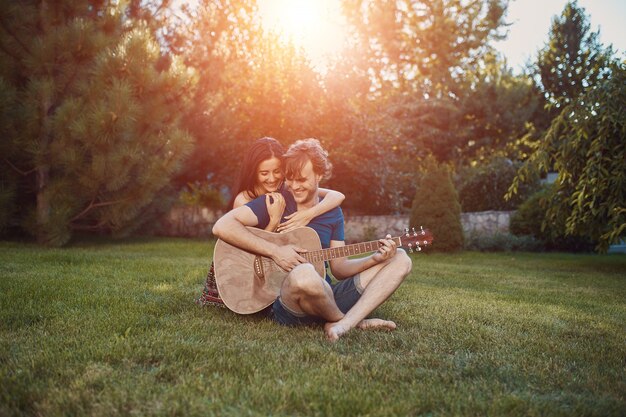 Couple romantique assis sur l'herbe dans le jardin