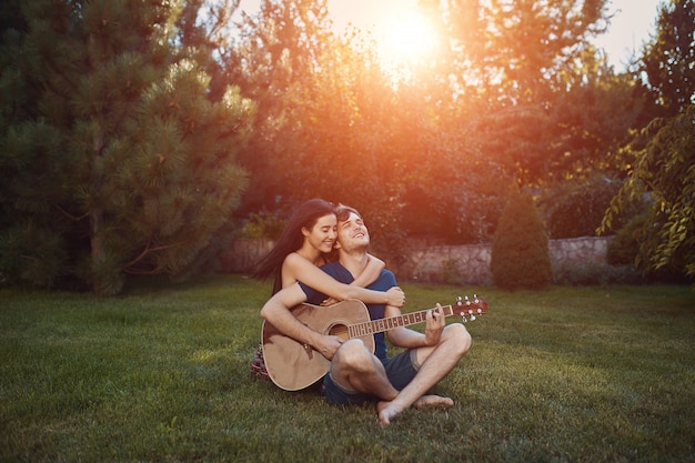 Couple romantique assis sur l'herbe dans le jardin