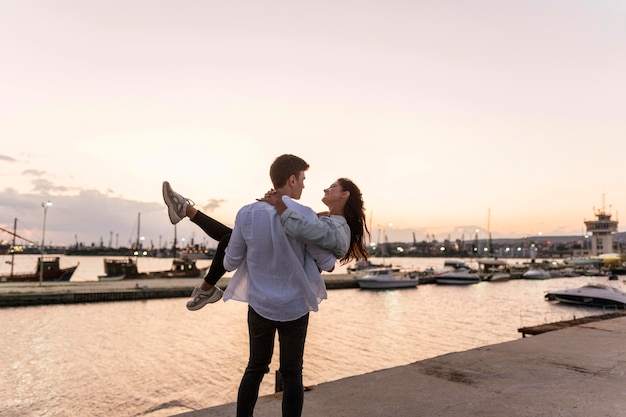 Photo gratuite couple romantique au coucher du soleil dans le port