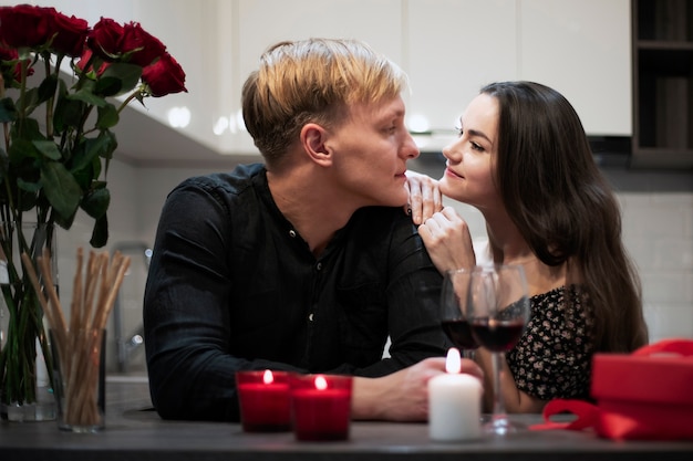 Photo gratuite couple romantique célébrant la saint-valentin à la maison avec du vin et un cadeau