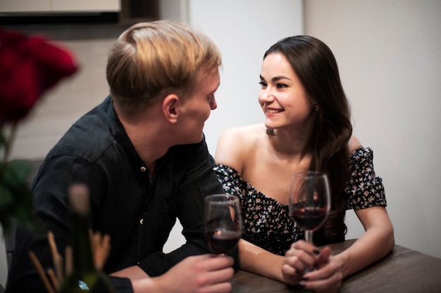 Couple romantique célébrant la saint valentin à la maison avec du vin