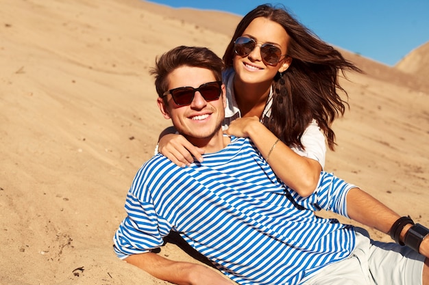couple romantique avec des lunettes de soleil couché sur le sable