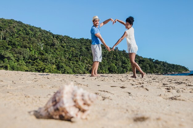 Couple romantique à la plage avec coquillage au premier plan