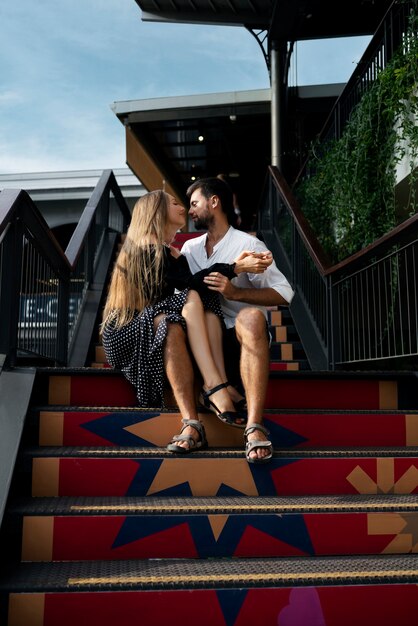 Couple romantique plein coup assis dans les escaliers