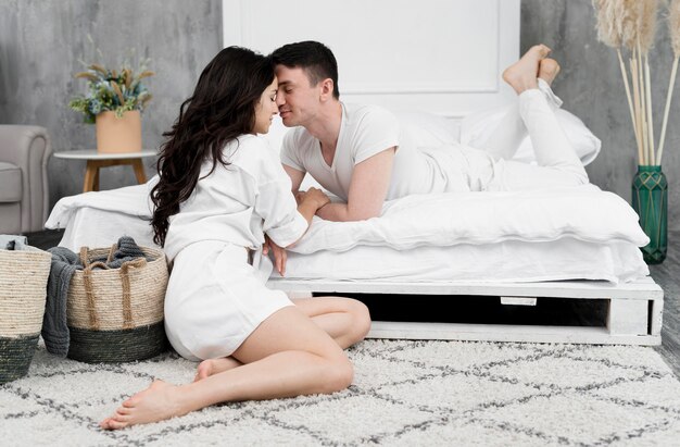 Couple romantique posant à côté du lit à la maison
