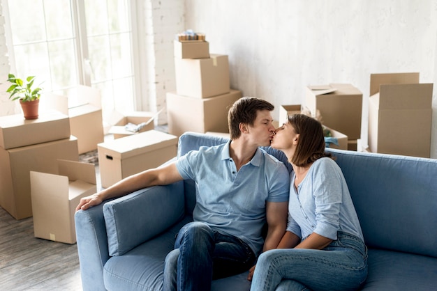 Couple romantique s'embrassant sur le canapé tout en se préparant à déménager