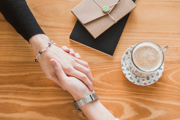 Couple romantique tenant la main et un café chaud sur la table en bois