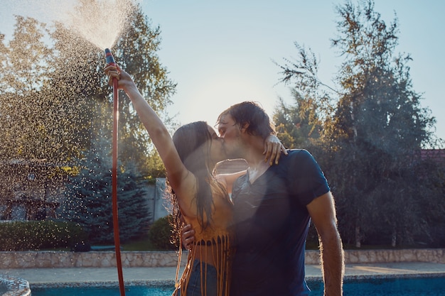 Photo gratuite couple s'amusant se verser avec un tuyau d'arrosage