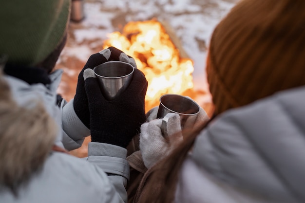 Couple s'échauffant à côté du feu sur la plage lors d'un voyage en hiver