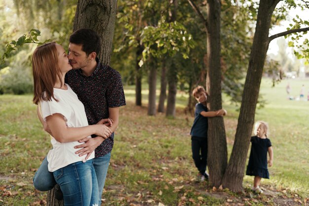 Couple s'embrassant pendant que leurs enfants regardent à l'extérieur