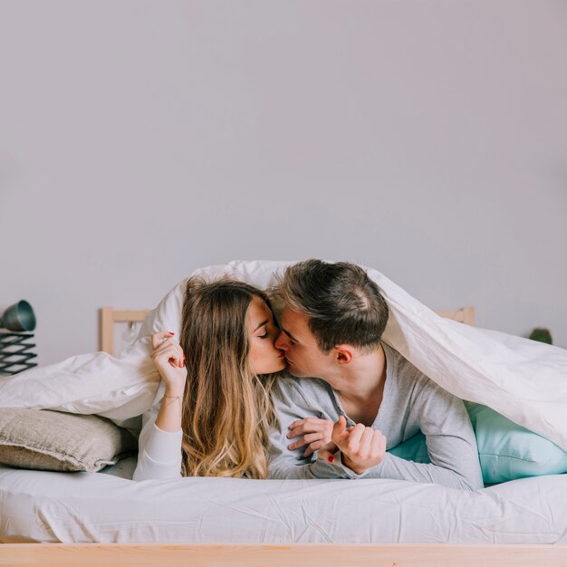 Couple s'embrassant sous la couverture
