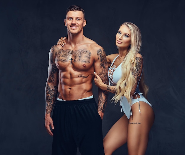 Couple Saint-Valentin, beau mâle tatoué et séduisante fille tenant par la main, posant en studio