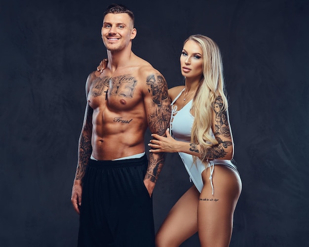 Couple Saint-Valentin, beau mâle tatoué et séduisante fille tenant par la main, posant en studio