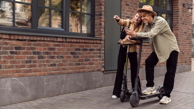Couple avec des scooters électriques à l'extérieur