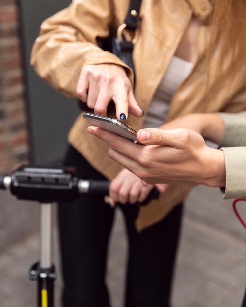 Couple avec des scooters électriques vérifiant le smartphone à l'extérieur