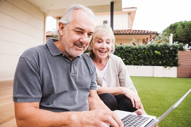 Couple Senior à l&#39;aide d&#39;un ordinateur portable dans le jardin