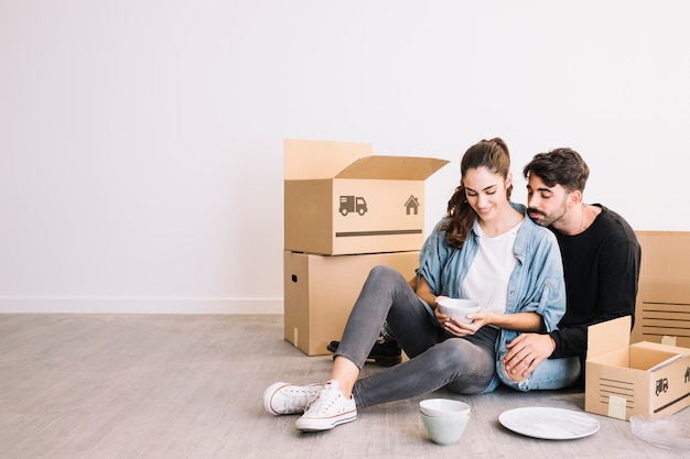 Photo gratuite couple avec smartphone devant des boîtes de déménagement