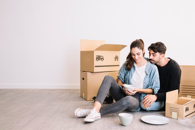 Couple avec smartphone devant des boîtes de déménagement