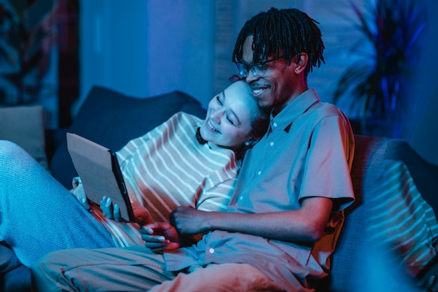 Couple de Smiley sur le canapé à l'aide de tablette