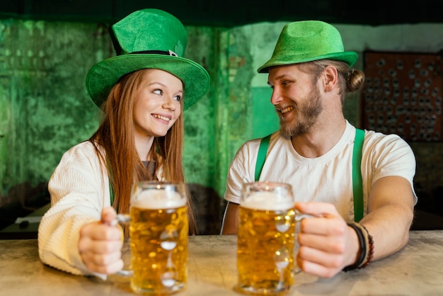 Couple Smiley célébrant st. patrick's day au bar avec boissons