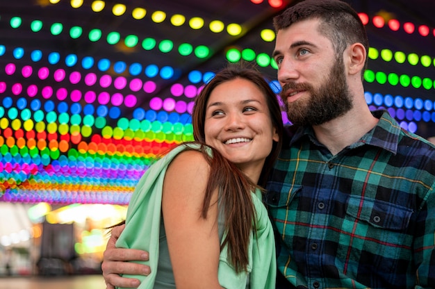 Photo gratuite couple de smiley étreignant au parc d'attractions