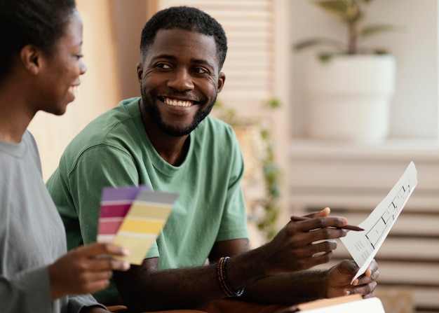 Photo gratuite couple de smiley faisant un plan à l'aide de la palette de couleurs pour redécorer la maison