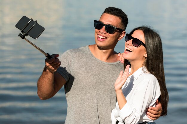 Couple de Smiley avec des lunettes de soleil prenant selfie à la plage