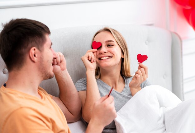 Couple de smiley de tir moyen avec du papier en forme de coeur