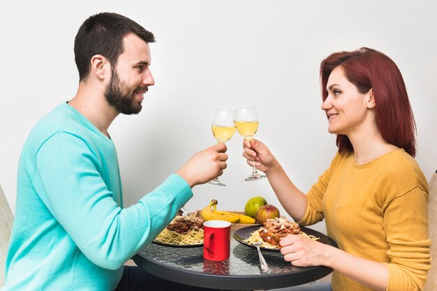 Couple souriant, appréciant la boisson avec de la nourriture à la maison