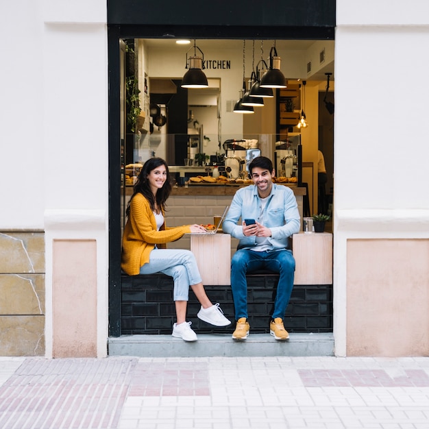 Couple souriant, assis dans la zone de la cafétéria ouverte